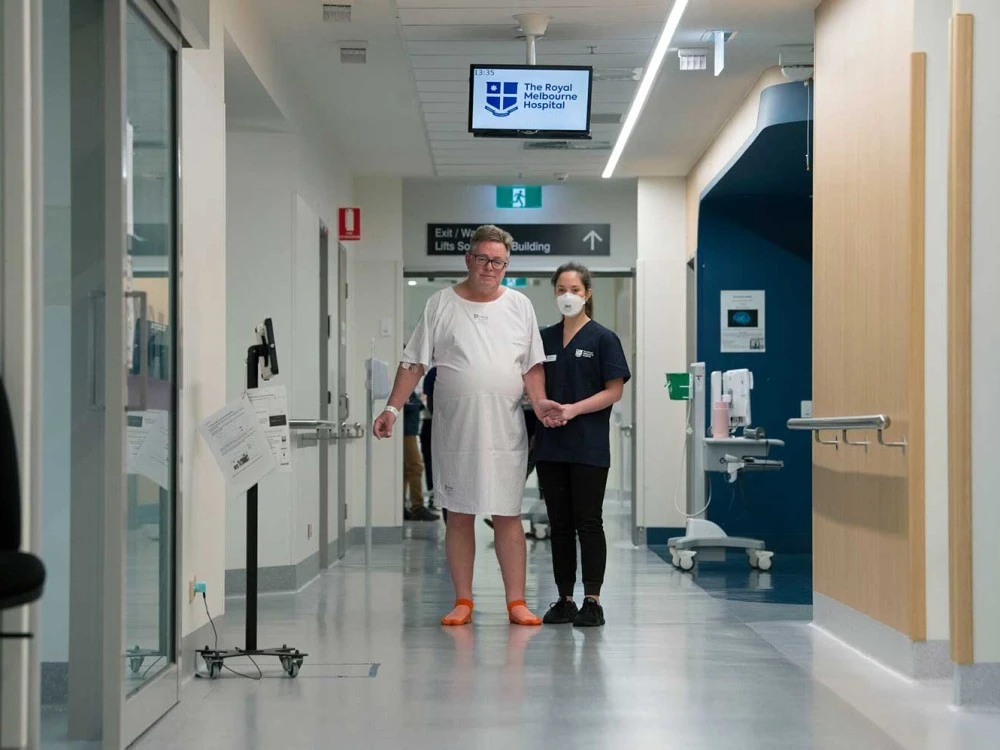 Male patient guided down corridor by physiotherapist