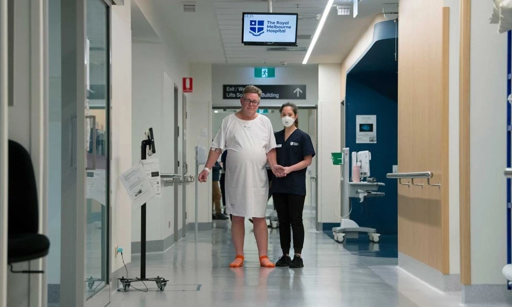 Male patient guided down corridor by physiotherapist