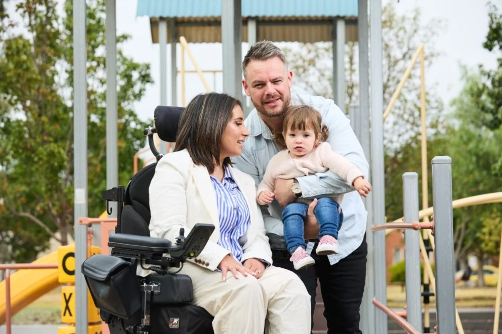 Brianna seated at playground with her family