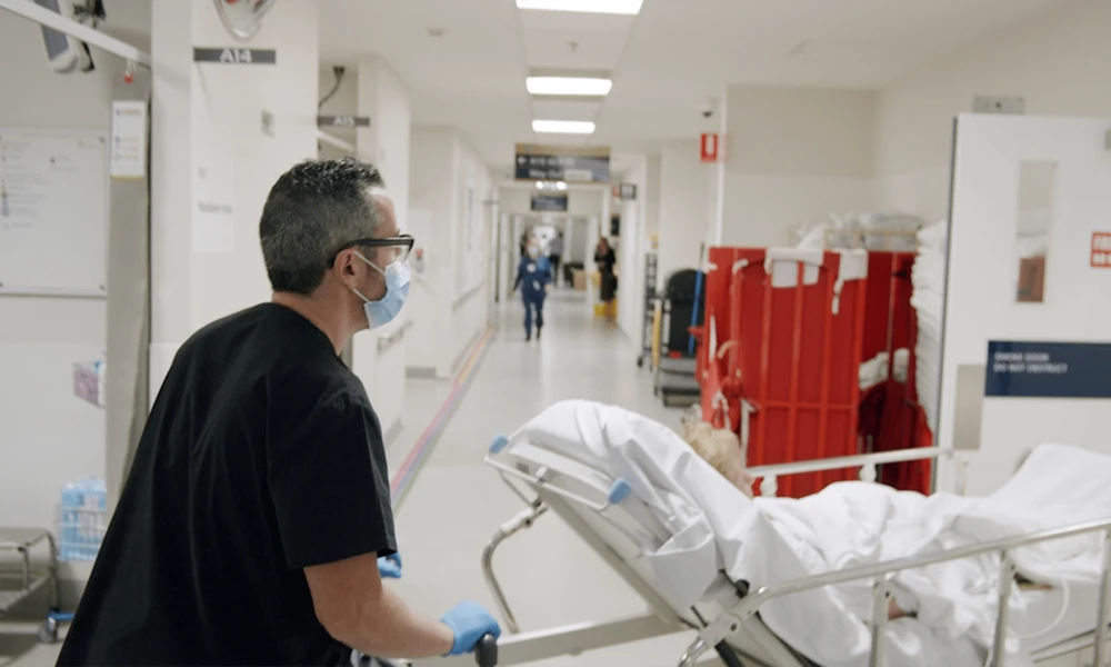 Clinical assistant moving patient from Emergency