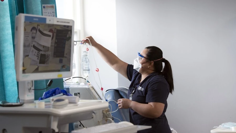 Dialysis nurse replacing IV bag for patient