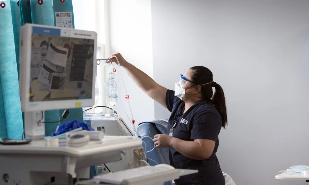 Dialysis nurse replacing IV bag for patient