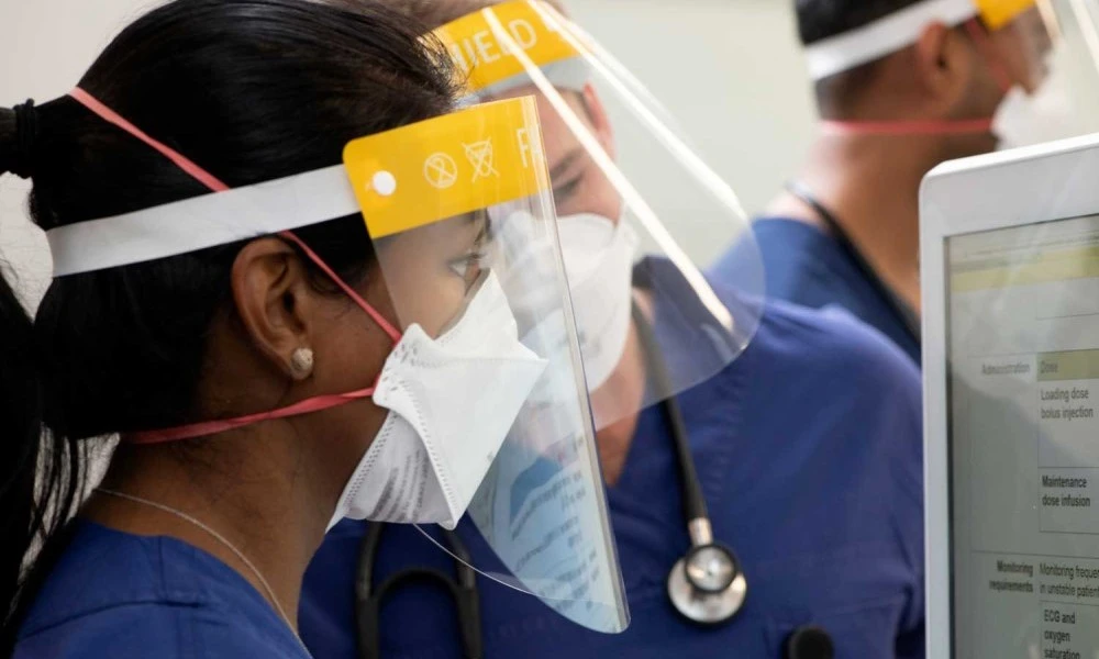 ICU staff in masks and shields looking at computer
