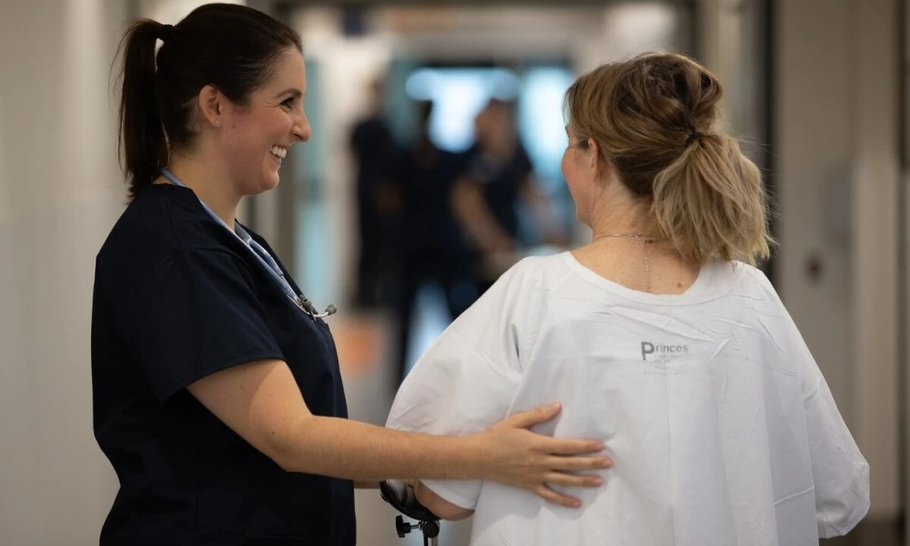 Nurse guides patient down hallway