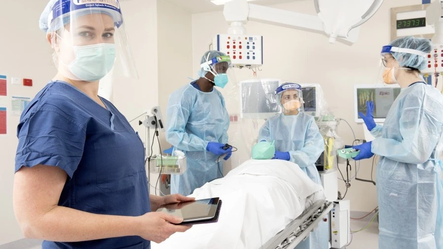 Four nurses in PPE training in a simulated hospital room