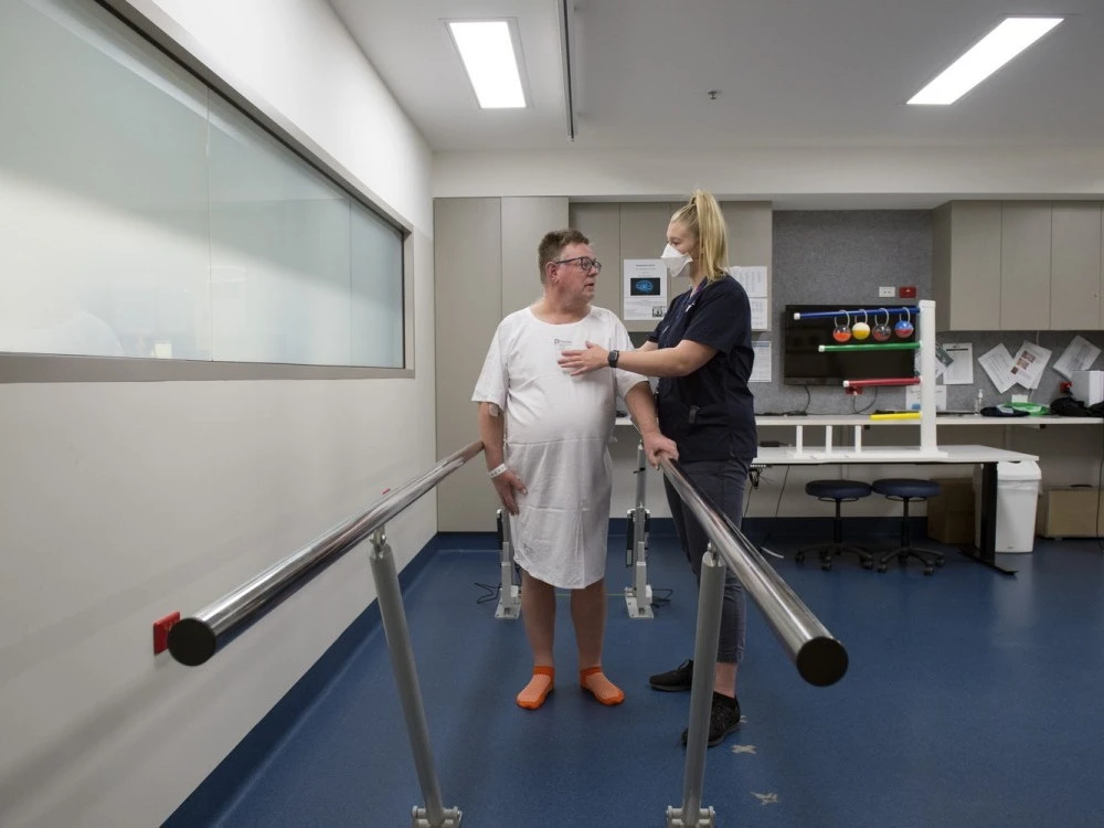 Neurology and Stroke physio assisting patient walking with bars