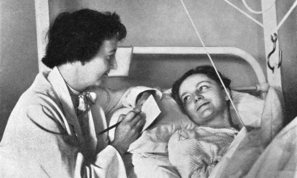 Social worker talking to patient in traction circa 1953