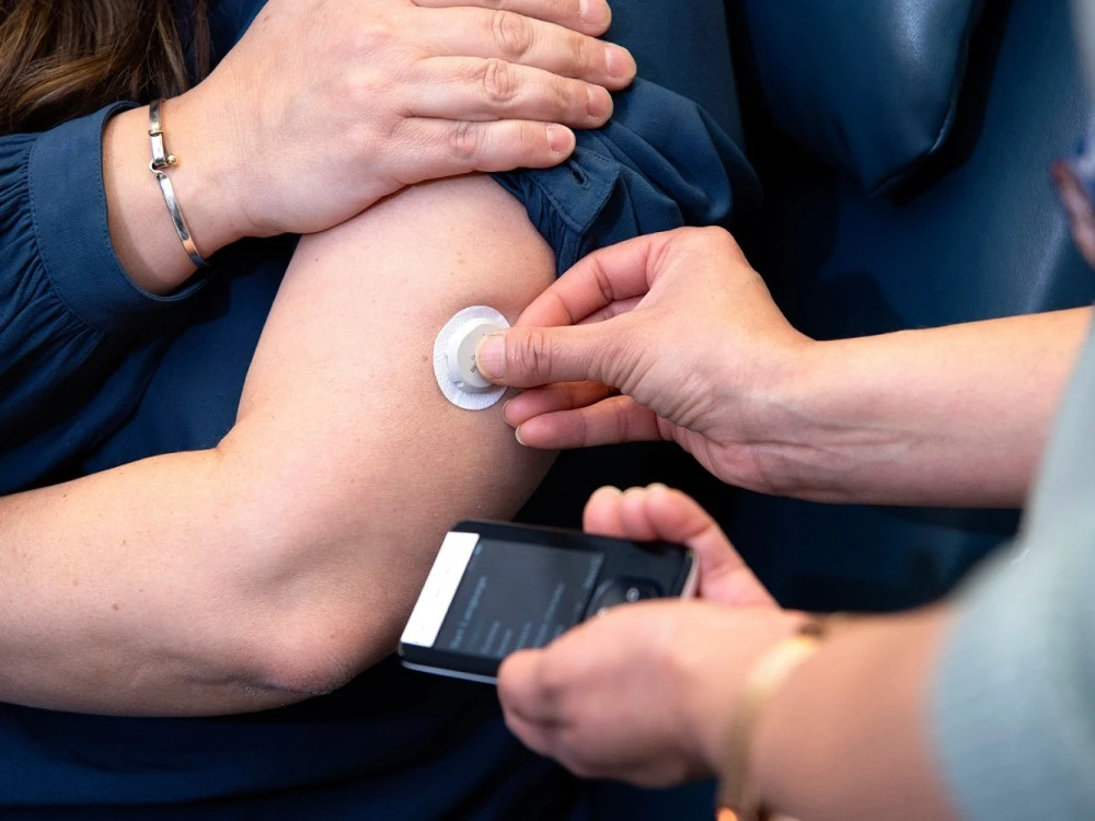 staff-member-applying-glucose-monitoring-device-to-patients-arm.jpg