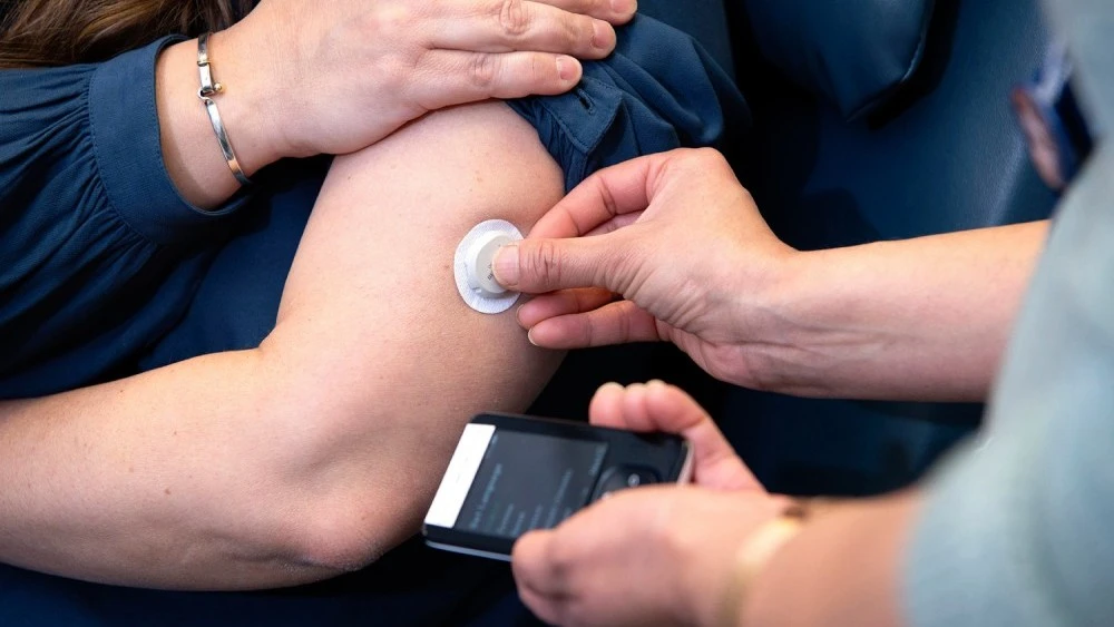 staff-member-applying-glucose-monitoring-device-to-patients-arm.jpg