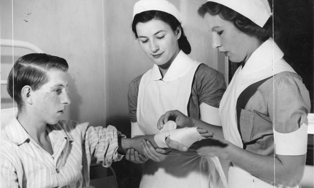 Two student nurses practising bandaging on a patient in 1948