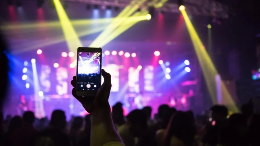 Hand using phone to take photo of stage at music festival