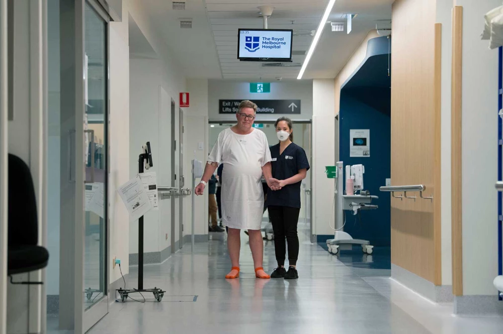 Male patient guided down corridor by physiotherapist