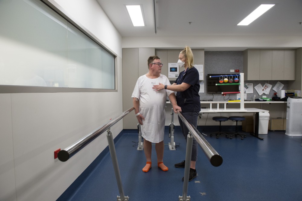 Neurology and Stroke physio assisting patient walking with bars