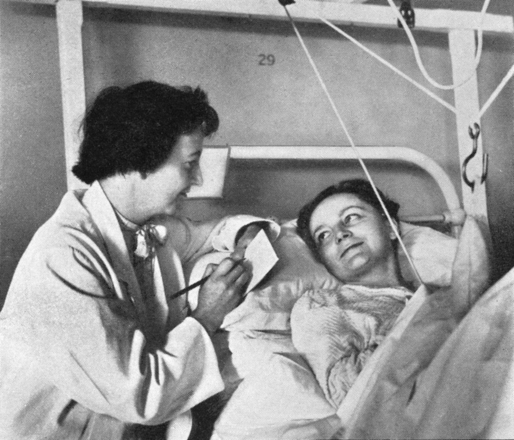 Social worker talking to patient in traction circa 1953